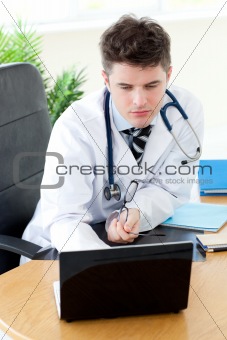 Confident male doctor using a laptop