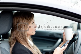 Blond businesswoman sending a text while driving