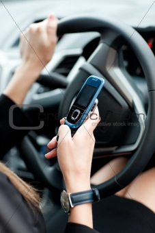Close-up of a businesswoman sending a text while driving