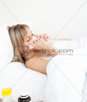 Sick woman blowing lying on a bed 