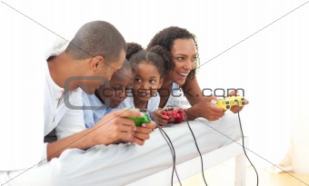 Lively family playing video game lying down on bed