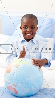 Smiling little boy holding a terrestrial globe