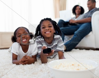Little siblings watching television and eating pop corn 