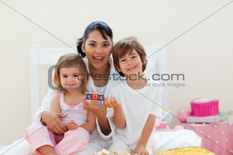 Attractive mother and her children playing with letters blocks