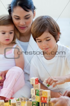 Mother and children playing with alphabetics blocks