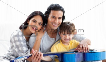 Caring parents playing guitar with their son