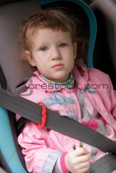Cute exhausted little girl in a baby car seat