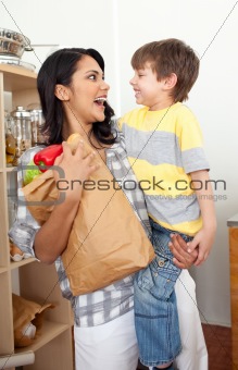 Cute Little boy unpacking grocery bag with his mother