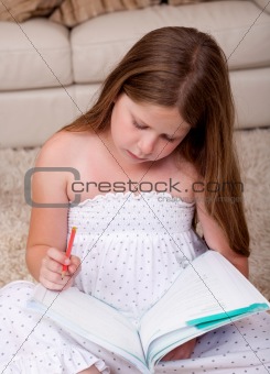 Young school girl reading book in living room