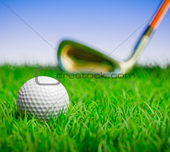 Golf ball with club in grass field