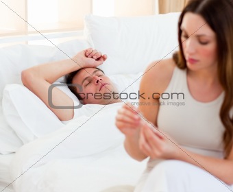 Concerned woman taking her sick husband's temperature