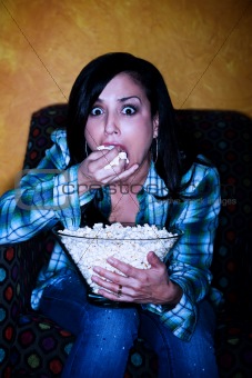 Pretty Hispanic woman with popcorn watching television