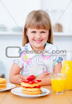 Joyful little girl eating waffles with strawberries 