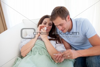 Concerned man taking his sick wife's temperature