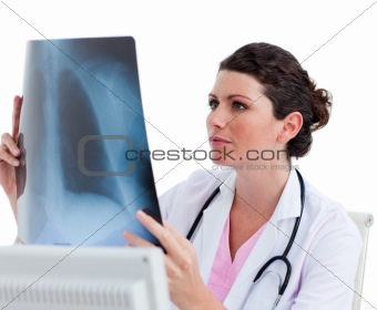 Pensive female doctor looking at X-ray in his office