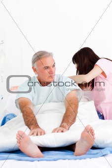 Female nurse adjusting pillows for a senior patient in a hospita