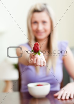 Portrait of a woman showing a strawberry