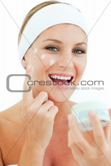 Caucasian woman putting cosmetic cream 