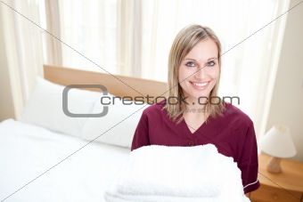 Radiant cleaning lady holding towels in a hotel room 