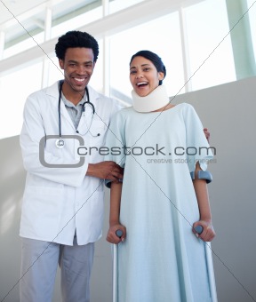 Smiling doctor helping a female patient on crutches