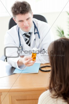 Young male doctor giving pills to a paient