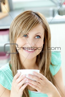 Self-assured woman holding a cup of coffee in the kitchen 