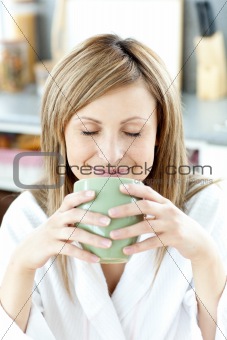 Delighted woman holding a cup a tea  in the kitchen
