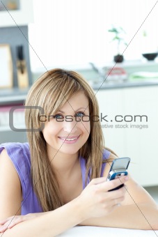 Teen woman sending a text in the kitchen 