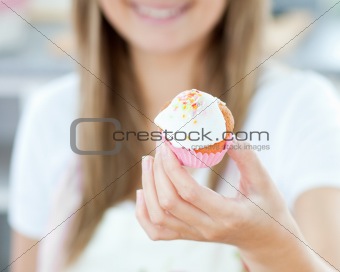 Delighted woman showing a cake in the kitchen