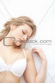 Asleep woman in underwear lying on bed