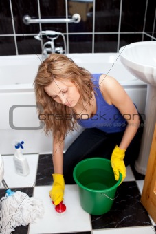 Caucasian young woman cleaning bathroom's floor