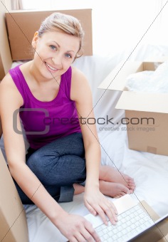 Smiling woman using a laptop in the living-room