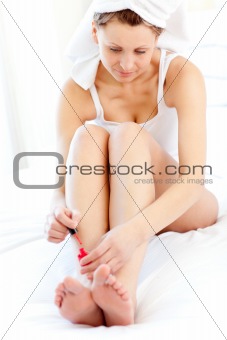 Radiant woman putting a nail varnish at home