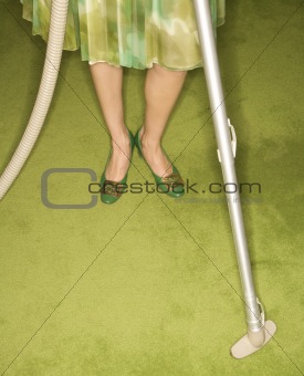 Woman vacuuming rug.