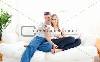 Adorable couple using a remote in the living-room