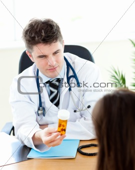 Young male doctor giving pills to a paient in his practice
