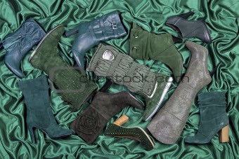 Female shoes and boots placed on green satin