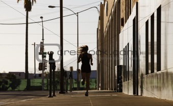 Woman running down a city block in the morning.