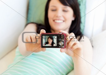 Attractive woman taking a picture of herself lying on bed 