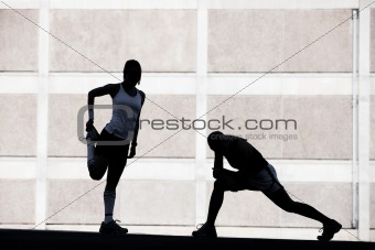 Two women stretching before running.