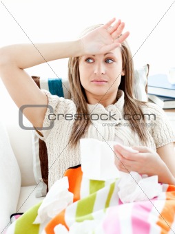 Sick young woman having fever lying on the sofa 