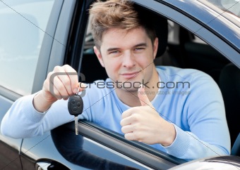 Charming young man holding a car sitting in his car 