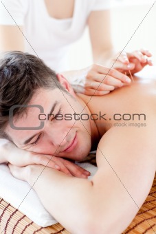 Charming young man in an acupuncture therapy in a Spa center 