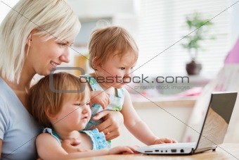 Astonished children looking at a laptop with their mother