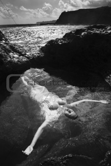 Nude woman floating in ocean.