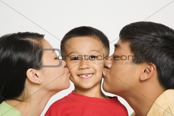 Parents kissing boy.