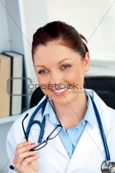 Happy female doctor holding glasses smiling at the camera