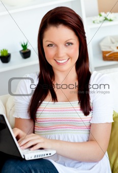 cheeful woman working with her laptop sitting at home