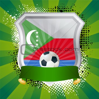 Shiny metal shield on bright background with flag of Comoros