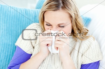 Morbid woman using a tissue sitting on a sofa